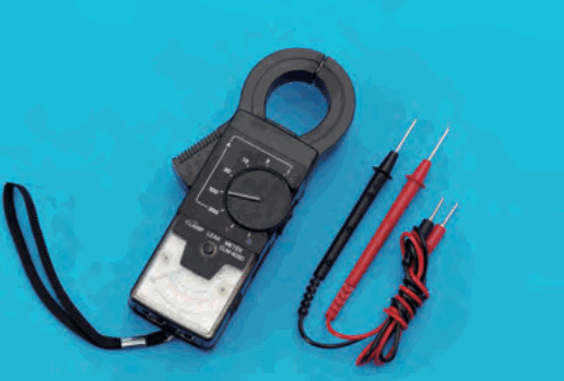 先端に輪の形の挟む部分がある黒い計器。CLAMP LEAK METER の字があり、ひもと赤と黒のリード線が付いている