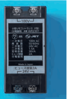 青い背景の黒い箱形の器具で、上下に端子があり、上の端子に 100V、下の端子に 24V の字、正面に 小型リモコントランス、WR2301、一次電圧 100V AC、二次電圧 24V AC、ヒューズ容量2A などの字とPSE・JETのマークがある