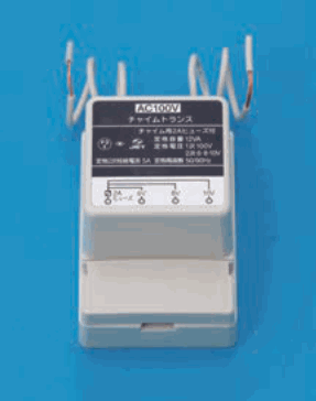 灰色の箱形の器具で、上から白い線が4本出ており、正面のラベルに AC100V、チャイムトランス などの字と端子の図がある