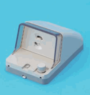 青い背景に置かれた灰白色の器具で,透明なふたの奥に差込口が1つあり(刃受が上下に2つ),下部に丸いつまみとねじがある