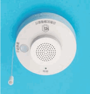 青い背景に置かれた白い円形の器具で、前面に小さな穴が多数ある丸い部分、SN の字のある丸い印、小さな字、小さな丸い窓があり、ひもが下がっている