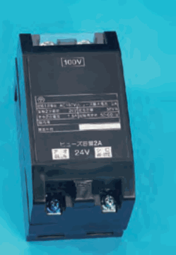 黒い箱形の器具で,上部に 100V の字の枠と銘板があり,下部に ヒューズ容量2A と 24V の字,端子ねじが2つある