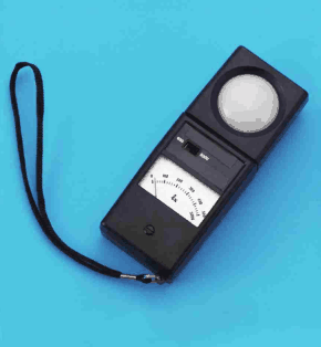 黒色の計器にひもが付いたもの。上部に白い半球形の受光部,下部に指針式の表示板がある