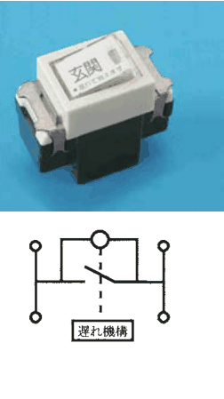 黒い胴の上に白いハンドルがある器具で,ハンドルに 玄関 の字と小さな字,右に小さな透明な窓がある。下の接点の構成の図は,左右に上下の端子を結ぶ縦線があり,その間を結ぶ線の途中に開いた接点と,それと並列に小さな丸を通る線があり,接点から下へ延びる破線の先に 遅れ機構 の字の枠がある