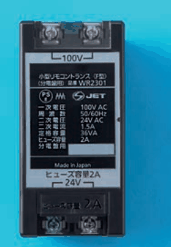 黒い箱形の器具。上と下にねじ端子が2つずつあり，上に 100V，下に 24V の字。銘板に 小型リモコントランス（F型）（分電盤用） 品番 WR2301，一次電圧 100V AC，周波数 50/60Hz，二次電圧 24V AC，二次電流 1.5A，定格容量 36VA，ヒューズ容量 2A，分電盤用，Made in Japan，ヒューズ容量2A の字がある