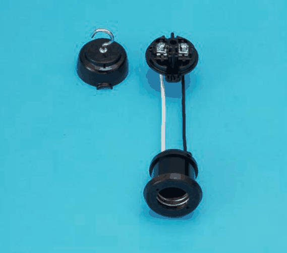 青い背景に置かれた黒色の器具。左上に上部に金属のフックが付いた丸いふた,右上に端子ねじが2つ見える丸い台があり,その台から白と黒の2本の線が下の黒い円筒形の部品につながっている。下の部品の口の内側にはねじ山の付いた金属が見える