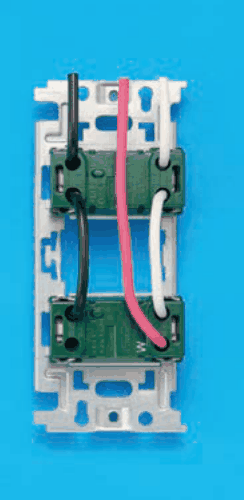 器具の裏面の写真。取付枠に上下2つの緑色の器具が付き，下の器具の右下にWの字がある。上から来た黒色の電線が上の器具の左の端子に入り，そこから黒色の渡り線が下の器具の左の端子へつながる。上から来た白色の電線が上の器具の右の端子に入り，そこから白色の渡り線が下の器具の右の端子へつながる。上から来た赤色の電線は上の器具を通らずに下の器具の右の端子に入る