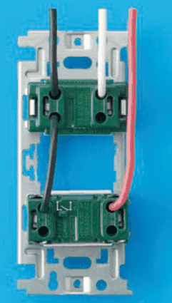 器具の裏面の写真。取付枠に上下2つの緑色の器具が付き，下の器具の表面に記号の刻印がある。上から来た黒色の電線が上の器具の左の端子に入り，そこから黒色の渡り線が下の器具の左の端子へつながる。上から来た白色の電線が上の器具の右の端子に入り，上から来た赤色の電線が上の器具を通らずに下の器具の右の端子に入る