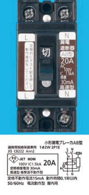 黒色の器具。上下に2つずつ端子ねじ，中央に切の字のハンドルとその下に丸い白色のボタン，左の帯に L の字と 定期的にテスト釦を押して動作確認をしてください，右の帯に N の字と 漏電遮断器 AB型 20A AC100V IC 1.5kA 感度 30mA 高速型 の字。下の銘板に 小形漏電ブレーカAB型，過負荷短絡保護兼用 1φ2W 2P1E，JIS C8222 Ann2，JET MDM 100V IC1.5kA 20A，定格感度電流 30mA 高速型 衝撃波不動作型，定格不動作電流15mA 動作時間0.1秒以内，50/60Hz 電流動作型 屋内用 の字と回路図がある