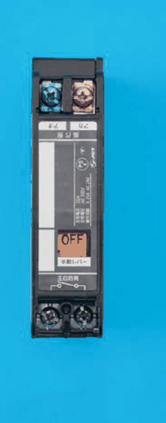 縦長の黒色の器具。上部に青色と赤色の端子ねじ2個,中ほどにOFFの字の黄色い窓と 手動レバー の字,下部に 主回路側 の字と接点1つの記号,その下に端子ねじ2個がある