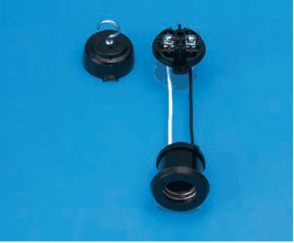 青い背景に置かれた黒い樹脂製の器具。左に上部に金属のフックが付いた丸いふた,右に金属の端子2つが見える丸い部品があり,その部品から白と黒の電線2本が下の黒い円筒形の受け口(内側に金属のねじ山)へつながっている