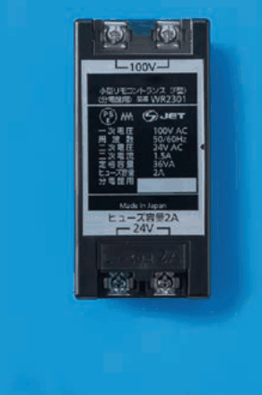 黒い箱形の器具で，前面に定格の表示があり，上に100V，下に24Vの字と端子2つずつがある