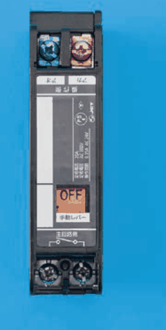 黒い縦長の器具で，上下に端子が2つずつあり，中ほどにOFFの表示の窓と手動レバーの字がある