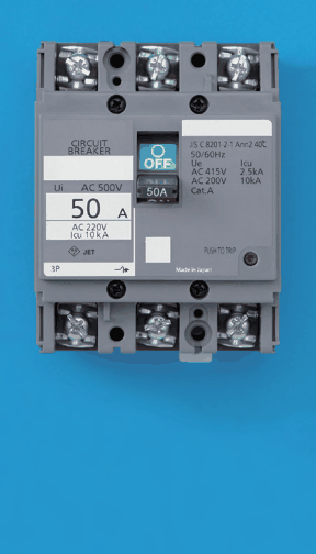 灰色の器具で上下に3つずつ端子がある。CIRCUIT BREAKER,AC 500V,50 A,3P の字と緑色のOFFのハンドルがあり,PUSH TO TRIPの赤いボタンがある