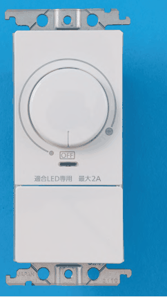 白い器具。上部に丸い回転つまみとOFFの表示，適合LED専用 最大2A の字がある